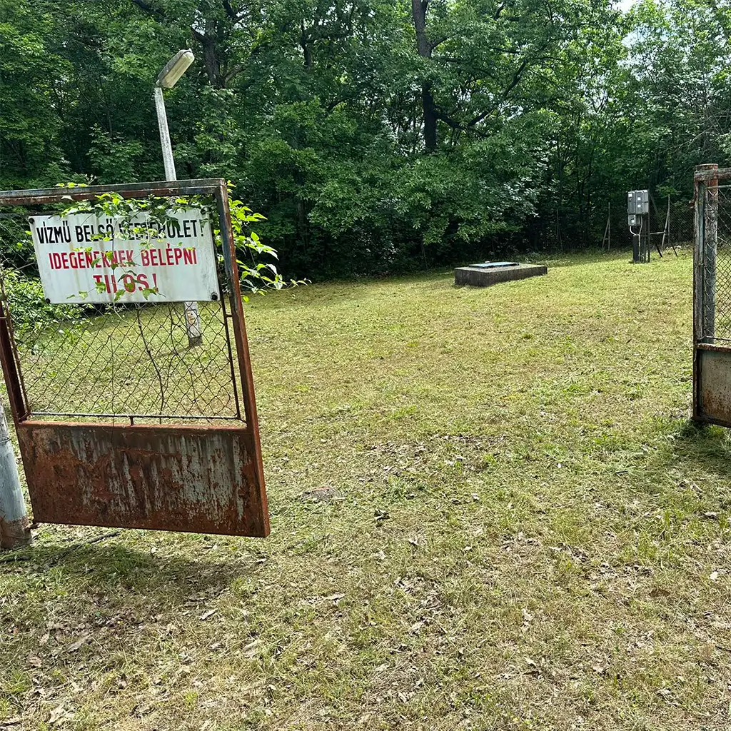 Az Edile IMB Kft. által nyírt fű egy vízmű zárt ipari területén – a kapun „Idegeneknek belépni tilos” tábla látható.
